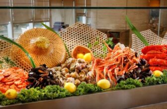 都會海逸酒店 Promenade「歲暮蟹香」自助餐官方宣傳圖 — 冰鎮海鮮檯上擺滿鮮紅蟹殼、龍蝦、貝類，伴檸檬、綠葉、紅色花卉與藤編飾物，滿滿螃蟹宴席擺盤（KKday 官方圖片）